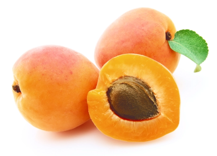 Ripe apricots with one halved showing the pit